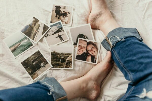 Los pies de un hombre en una cama contemplando varias fotografía Polaroid del producto de imprimir fotos Polaroid online con Imprimir Fotos Granada