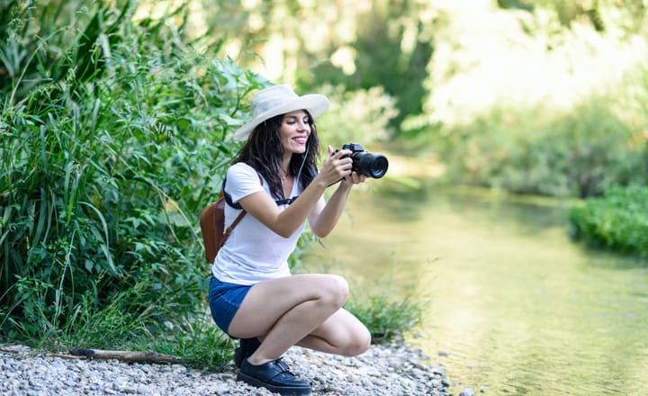 una mujer realizando fotos con una cámara sin espejo en un río